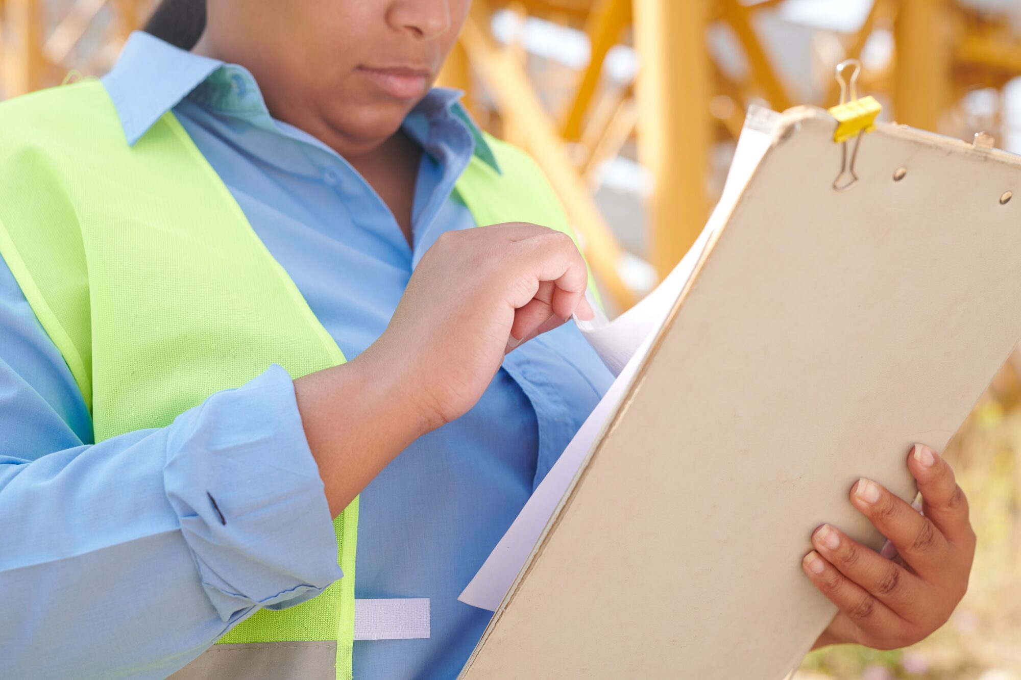 An engineer in safety gear reviewing project documents on a clipboard at a construction site